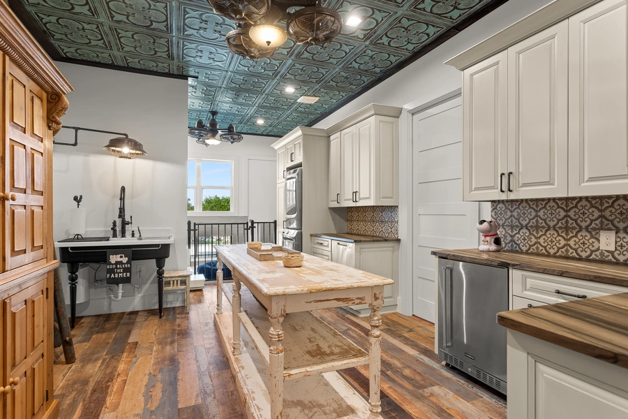Charming casita kitchen at 1534 Circolare with white shaker cabinets, reclaimed wood flooring, decorative tin ceiling, and butcher block countertops