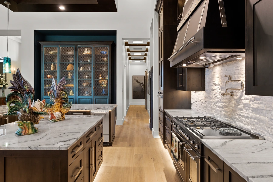 Kitchen detail at 1534 Circolare featuring a professional range, custom hood, stone backsplash, and illuminated blue china cabinet