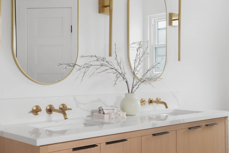 Modern bathroom with double oval mirrors and brass fixtures