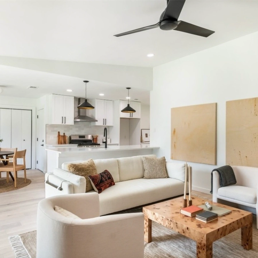 Modern open concept living room and kitchen with white cabinetry, custom lighting, and contemporary furniture