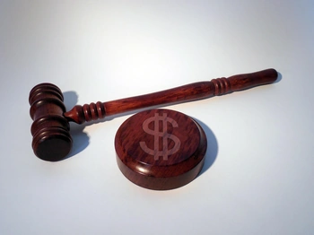 A wooden gavel and a symbol of a dollar sign on a white background, representing the legal and financial aspects of a law practice.