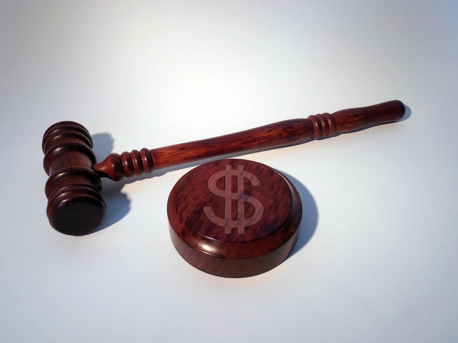 A wooden gavel and a symbol of a dollar sign on a white background, representing the legal and financial aspects of a law practice.