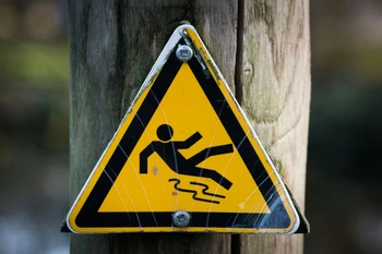 Slip and fall warning sign on a wooden post