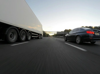 Car driving next to an 18-wheeler on the highway